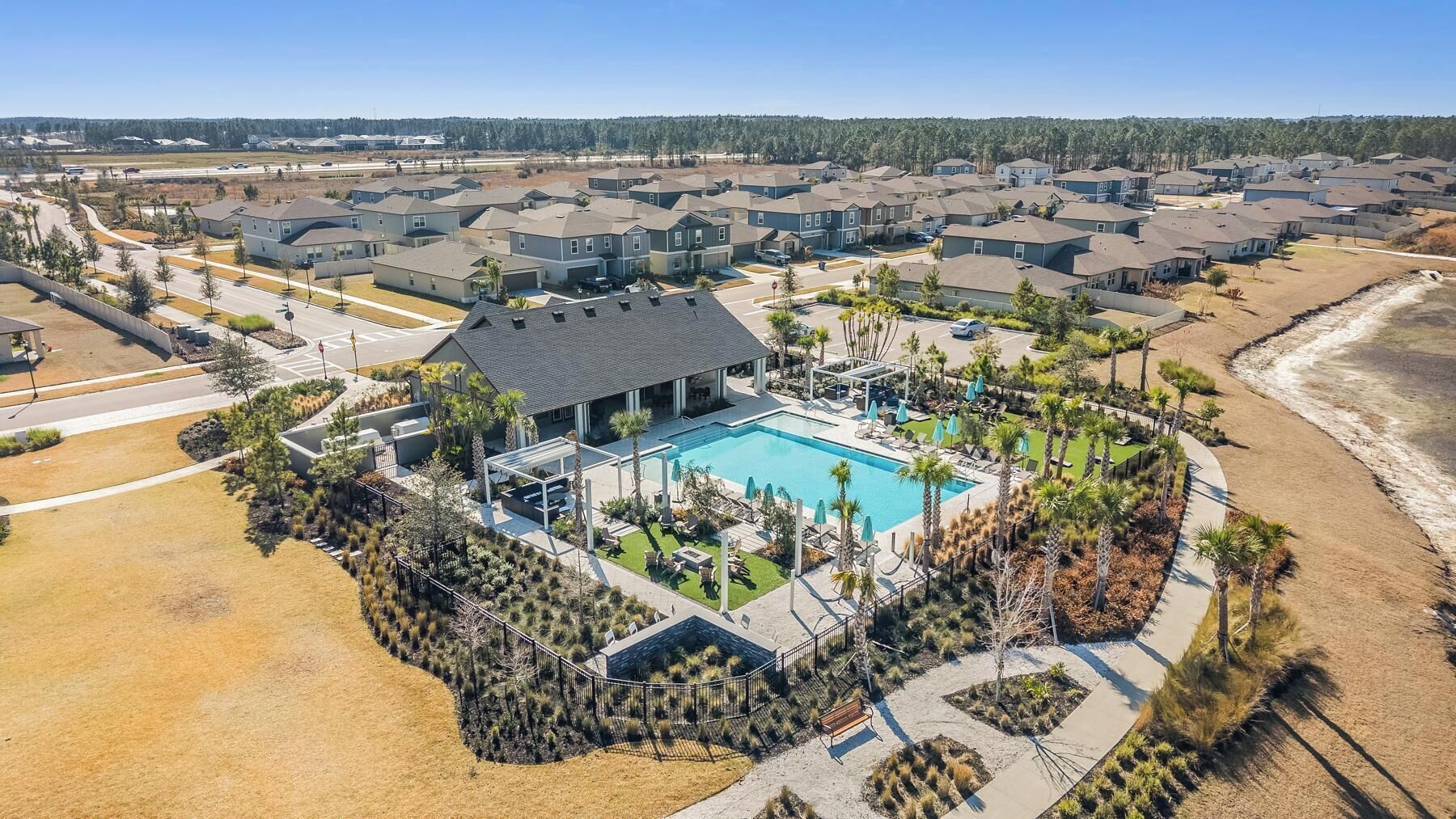 A residential area with a swimming pool, houses, and a beach.
