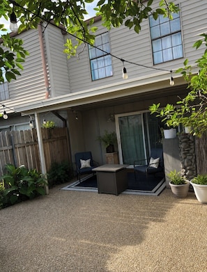 A house with a covered patio, outdoor seating, a wooden fence, and potted plants. - Lovely 2-bedroom Townhome, Baton Rouge (Baton Rouge)