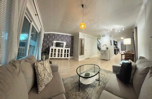 A living room with a sofa, a glass coffee table, and a TV on a stand. - Lovely 2-bedroom Townhome, Baton Rouge (Baton Rouge)