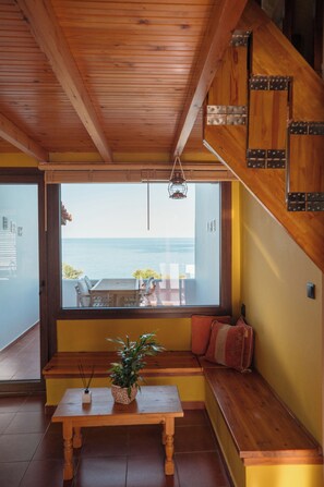 Un banco de madera con una planta en maceta, una mesa y vista al mar.