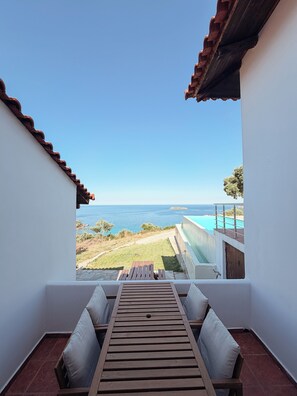 Un balcón con vista al mar, una mesa de madera y dos sillas.