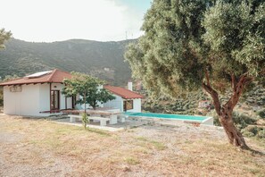 A house with a swimming pool, a patio, and a view of the surrounding hills.