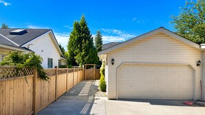 A residential driveway leading to a garage with a wooden fence and a clear sky.