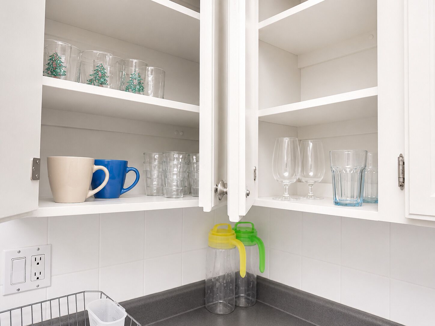 A kitchen with white cabinets, a metal rack, and a power outlet.