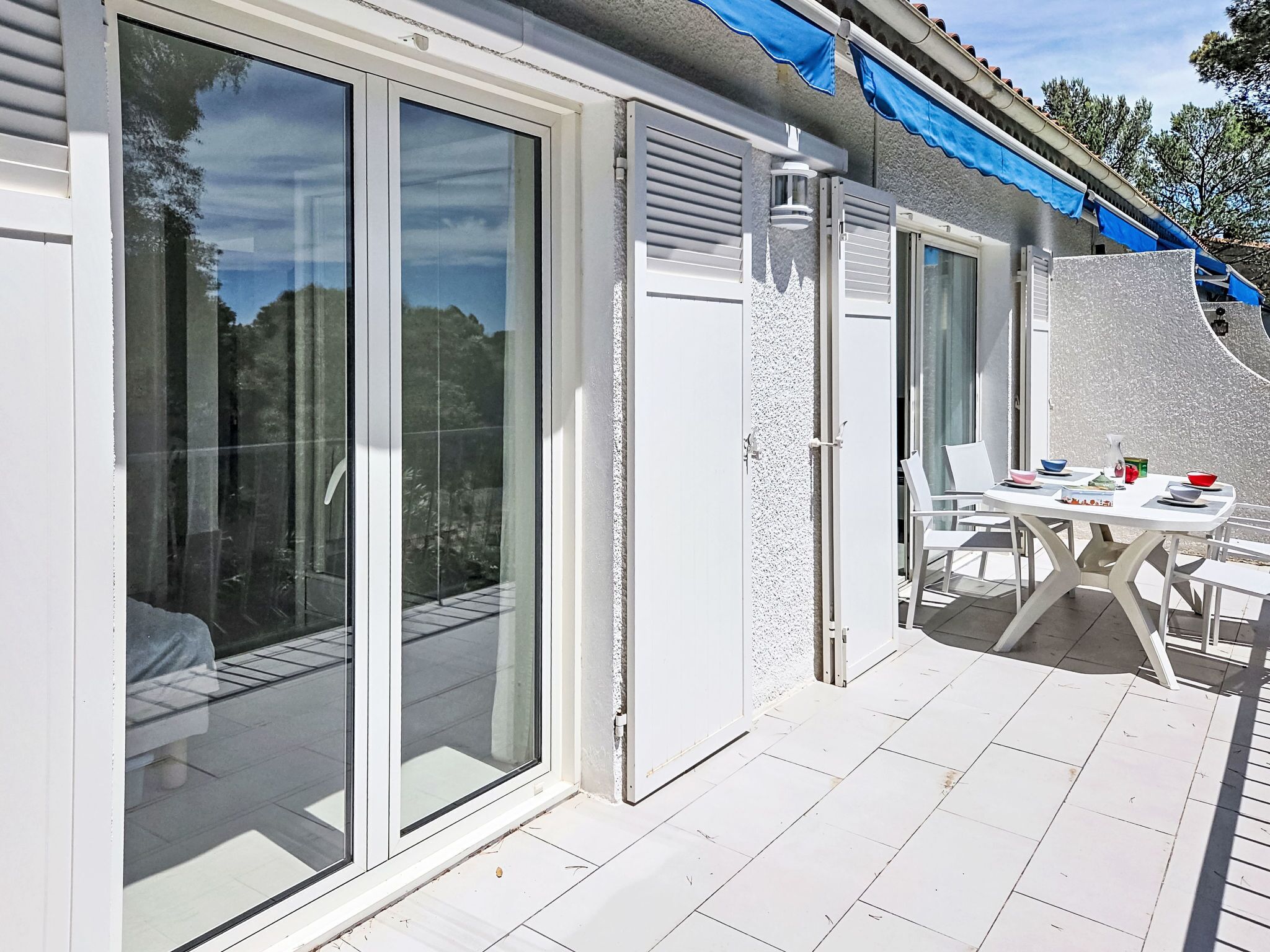 A patio area with a table and chairs, a sliding glass door, and a blue awning.