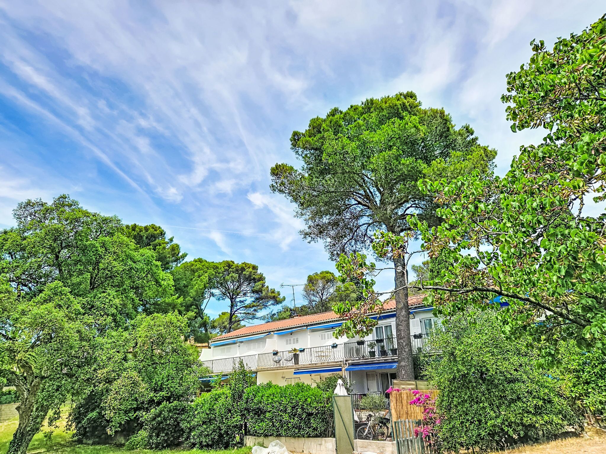 A residential building with a balcony, surrounded by lush greenery and trees.