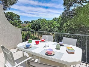 Ein Balkon mit einem für Tee gedeckten Tisch, umgeben von Grünpflanzen und Bäumen.