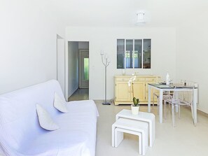 Habitació moderna amb un sofà blanc, una taula petita blanca, un armari i una finestra.
