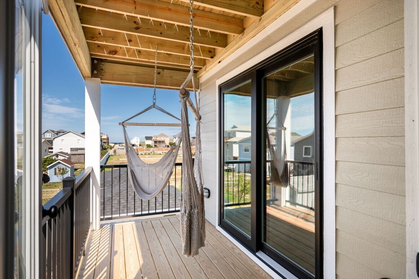 En balkon med hængekøje, træterrasse og udsigt til omkringliggende huse.