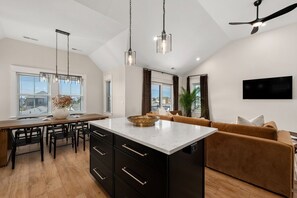 A modern kitchen with a central island, black cabinetry, and pendant lighting. - Luxury Home! Steps To Beach - Pool - Dog Friendly! (Kill Devil Hills)