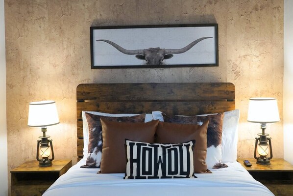 A bed with a wooden headboard, two bedside lamps, a framed skull picture, and two pillows with 'HONDOL' text.