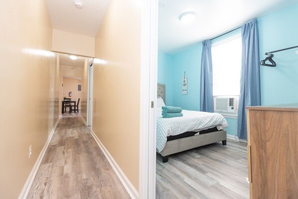 Un couloir menant à une chambre à coucher équipée d’un lit, d’un bureau et d’une chaise.