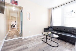 Un salon moderne avec un canapé, une table basse et un couloir menant à une salle à manger.