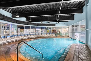 An indoor swimming pool with a tiled floor, a metal pool ladder, and a ceiling with exposed beams and ductwork. - Fully Renovated Beachfront Condo-Tiki Bar-3 Pools (Destin)