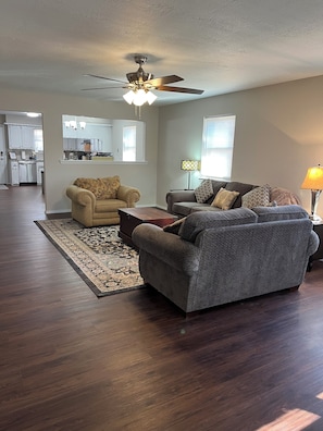 A living room with a ceiling fan, two sofas, a coffee table, and a rug.