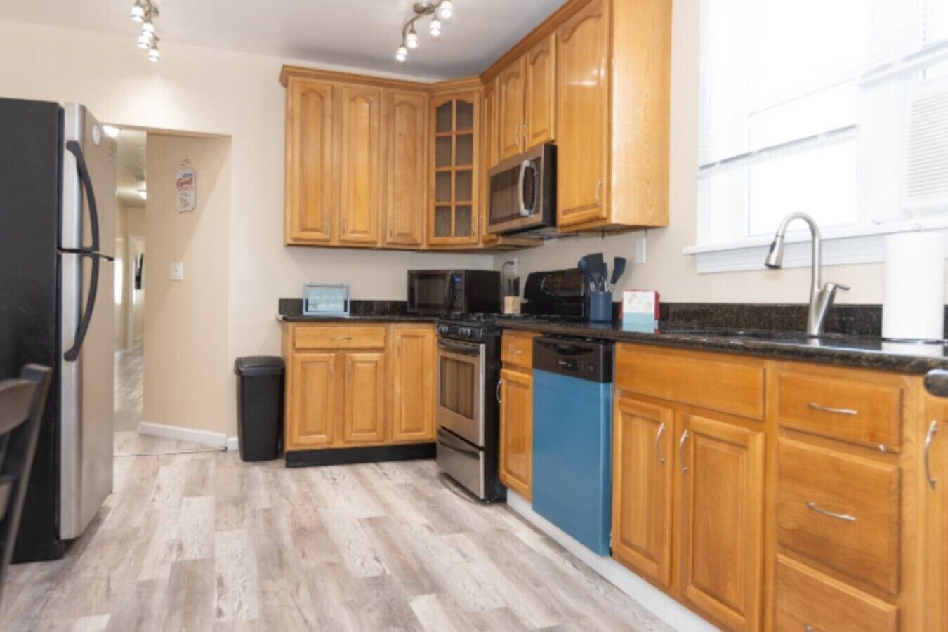 A kitchen with wooden cabinets, a microwave, a dishwasher, and a refrigerator.