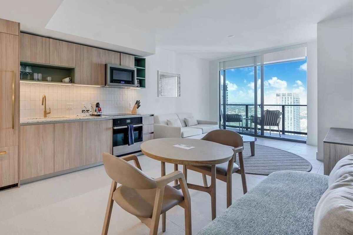 A modern apartment with a kitchen, dining area, and a balcony with a city view.