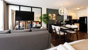 Una sala de estar moderna con sofá, mesa de comedor, sillas y una cocina equipada.