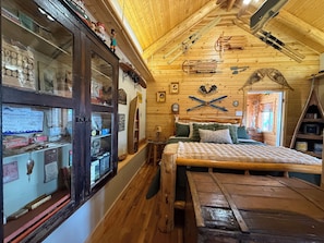 A wooden interior with a bed, a cabinet with hooks, and skis mounted on the wall.