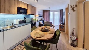 Eine moderne Küche mit Essbereich, Holzschränken und einem kleinen Tisch mit gewebten Platzdeckchen.