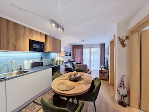 Eine moderne Küche mit Essbereich, Holzschränken und einem kleinen Tisch mit gewebten Platzdeckchen.
