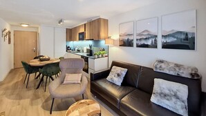 Ein modernes Wohnzimmer mit einer Couch, einem Esstisch mit Stühlen, einer Küchenzeile und Kunstwerken an den Wänden.