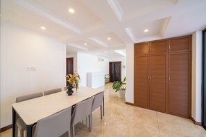 A dining area with a table and chairs, a potted plant, and a wooden wardrobe. - Tyms 3BR 2BA Tianhe Garden Near Metro (Shanghai)