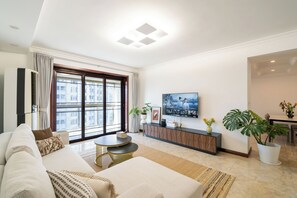 A modern living room with a sofa, a coffee table, a TV, and a large window. - Tyms 3BR 2BA Tianhe Garden Near Metro (Shanghai)