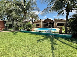 Un jardin avec une piscine, des palmiers et une maison en briques.