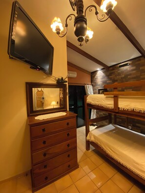 Camera da letto con televisore, comò in legno, letti a castello e lampadario.