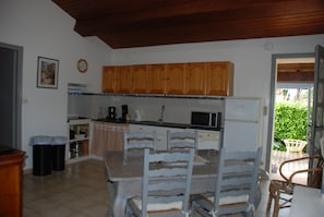 Une cuisine avec des meubles de rangement en bois, un four à micro-ondes et une table à manger avec des chaises.