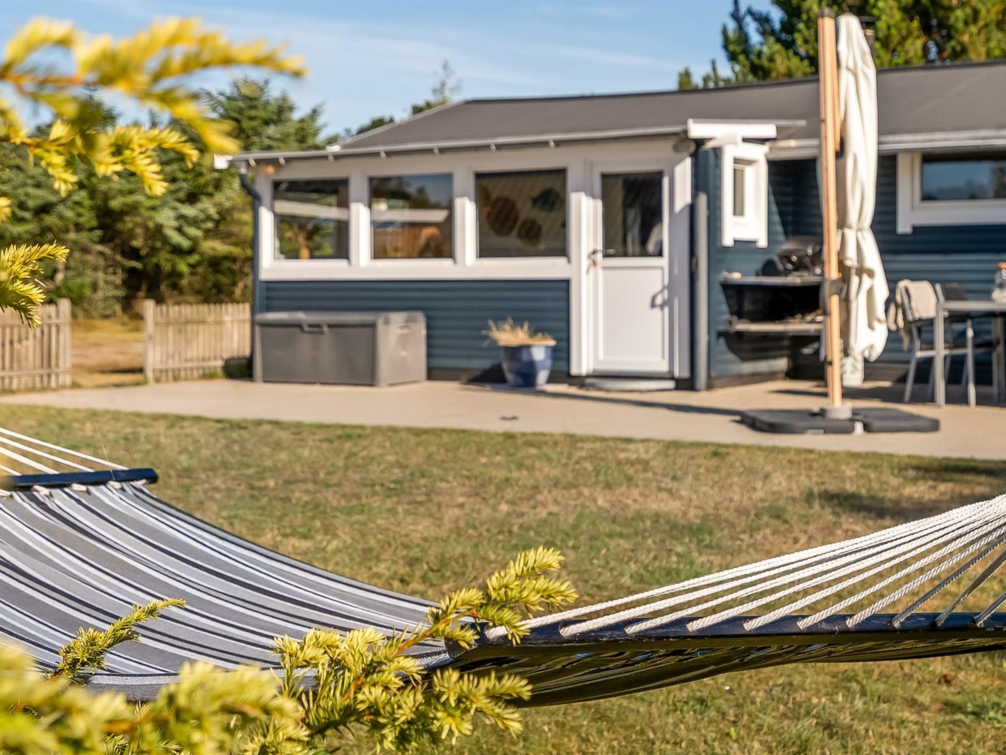 A house with a covered patio, a barbecue area, and a hammock in the foreground.