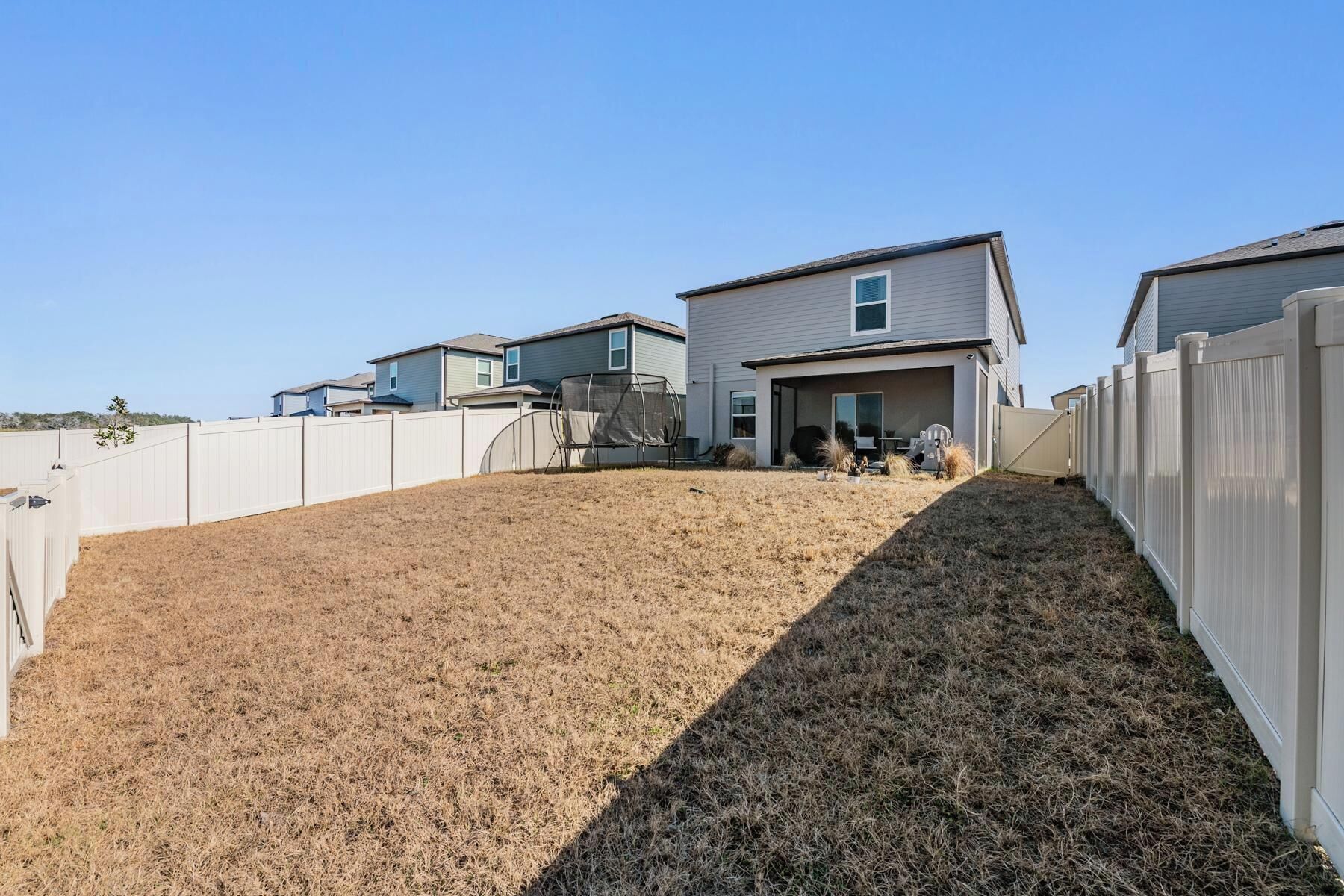 A residential area with houses, a fenced yard, and a clear sky.