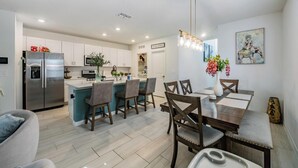 Una cocina moderna con un refrigerador empotrado, un comedor con sillas de madera y una isla central.