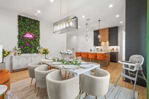 Eine moderne Küche mit Essbereich, hoher Decke und einer Neonreklame an der Wand.