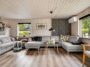 A modern living room with a grey sectional sofa, a round coffee table, and a stone accent wall. - "Melisande" -  from the sea by Interhome (Storvorde)