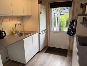 A compact kitchen with a sink, a refrigerator, and a window. - "Melisande" -  from the sea by Interhome (Storvorde)