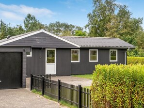 Un bâtiment d’un seul étage, à l’extérieur sombre, avec une porte de garage et un petit espace porche.