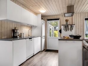 A modern kitchen with white cabinetry, a coffee maker, and a window overlooking greenery. - "Melisande" -  from the sea by Interhome (Storvorde)