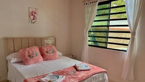 A bedroom with a bed, pillows, a window with curtains, and a wall-mounted picture. - Cozy country house with swimming pool and comfort only 5 min. from the city. (Villavicencio)