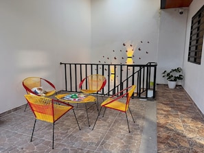 A balcony with wicker chairs, a table with magazines, and a potted plant.