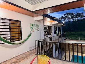 A balcony with a pool, a hammock, and a chair.