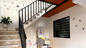 A staircase with a black railing, a wall with butterfly decals, a window with bars, and a decorative item on the wall. - Cozy country house with swimming pool and comfort only 5 min. from the city. (Villavicencio)