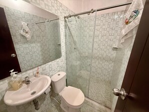 A bathroom with a sink, toilet, and glass shower enclosure.