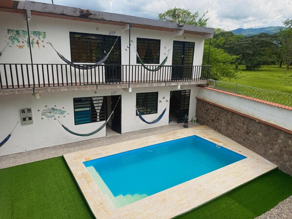 Una casa de dos pisos con piscina, balcón y jardín.