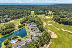 Luftaufnahme eines Golfplatzes mit Schwimmbad, Parkplatz und Wohnhäusern.