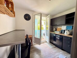 A compact kitchen with a dining area, a clock, and a view of greenery outside. - Two-bedroom apartment within a 10-minute walk of downtown (Aix-en-Provence)