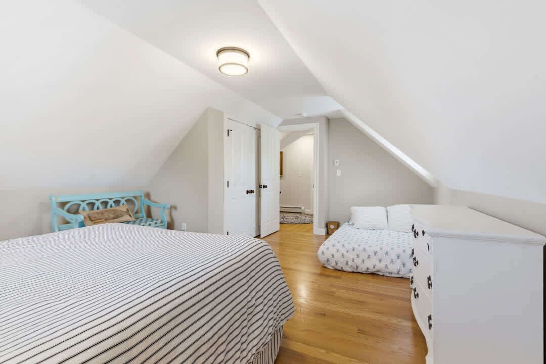 Een slaapkamer met een bed, een stoel, een nachtkastje en een kledingkast.