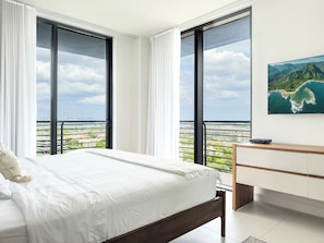 Ein Schlafzimmer mit einem Bett, einem Schreibtisch und einem großen Fenster mit Blick auf die Stadt.