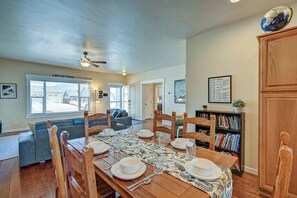 A dining area with a wooden table set for four, surrounded by wooden chairs. A ceiling fan is visible above the table, and there is a bookshelf with books to the right. - Basecamp for your Buena Vista Adventures! STR-022 (Buena Vista)